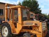 un tracteur jaune garé sur la terre battue