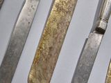 five different types of silverware on display in a display case