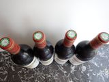 four bottles of wine are lined up on a marble table