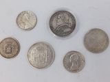 six different coins are arranged in a row on a white surface