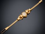 une image représentant un bracelet en or orné de perles sur fond noir