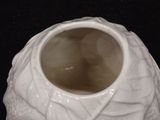 a white vase with a leaf design on it