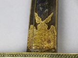a close up of a gold and black sword on a white surface