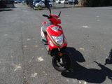 a red scooter parked in a parking lot next to a person