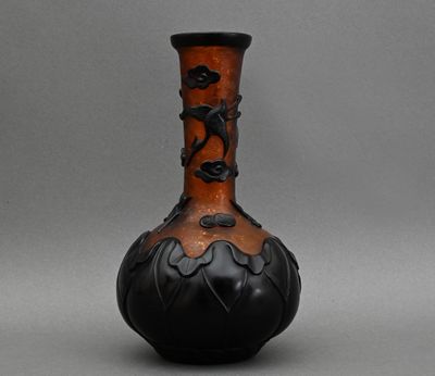 un vase noir et orange posé sur une surface grise