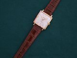 a watch on a green surface with a brown strap