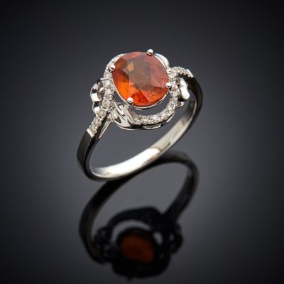 an orange sapphire and diamond ring on a black surface