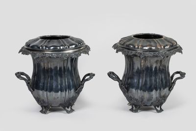 deux vases en argent munis d'anses, posés sur un fond blanc