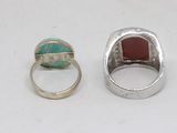 two rings and a ring with a red stone on a white surface