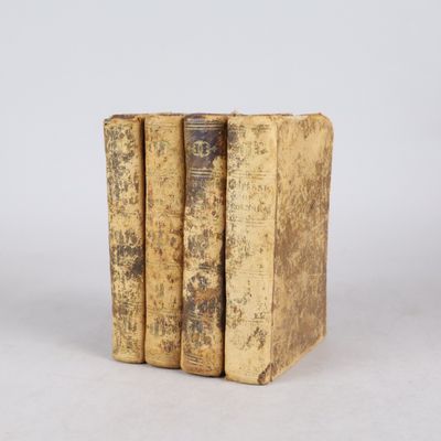 trois vieux livres empilés sur une surface blanche