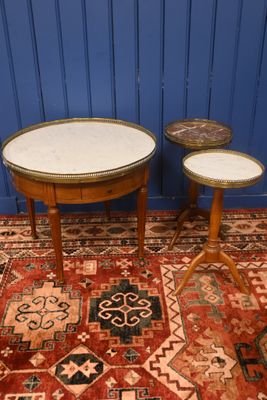 Deux tables au plateau en marbre sont posées sur un tapis devant un mur bleu.