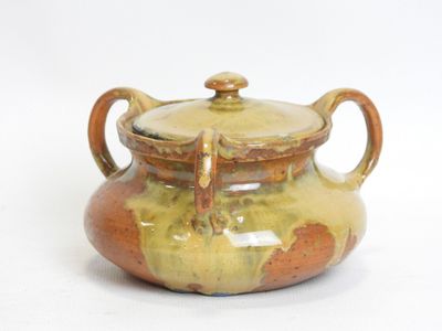 a brown and yellow pot with a lid on a white surface