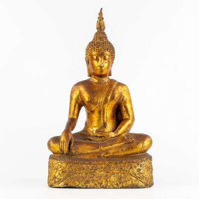 une image représentant une statue de Bouddha en or posée sur un bloc de bois
