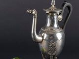 une théière ancienne en argent ornée d'une fleur sur fond noir