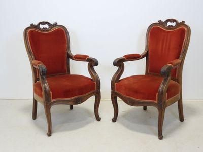 paire de fauteuils recouverts de velours rouge, avec des accoudoirs en bois sculpté