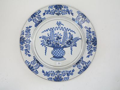 une assiette bleue et blanche sur laquelle est représenté un vase de fleurs