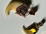 two pieces of jewelry sitting on a white surface