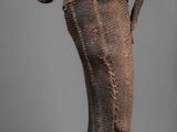statue of a man holding a banana on a wooden base