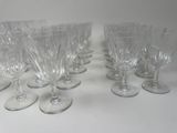 six clear wine glasses are lined up on a white surface