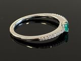 an image of a diamond and emerald ring on a black surface