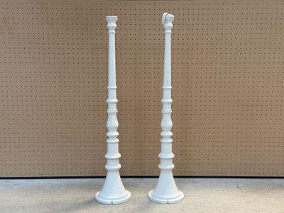 une paire de bougeoirs blancs exposés devant un mur