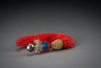 a close up of a red and gold bracelet with a bell on it