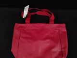 a red purse with a tag on it sitting on a black surface