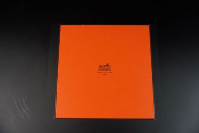 une boîte orange posée sur une surface noire, avec un fond noir