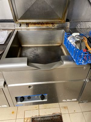 un évier en inox dans une cuisine où se trouve un panier rempli d'ustensiles