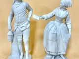 deux statues représentant un homme et une femme se serrant la main devant un fond beige