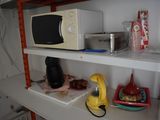 a shelf with a microwave, a kettle, and other kitchen items on it