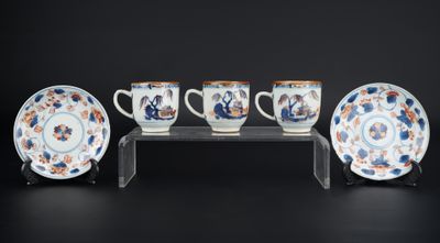 trois tasses et une soucoupe posées sur un présentoir, sur fond noir