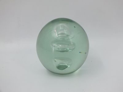 une boule de verre verte posée sur une surface blanche