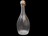 a clear glass bottle with a gold top on a black background