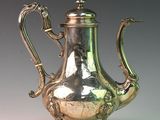 a silver tea pot sitting on a stand on a table