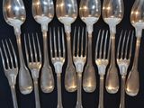 a lot of silver spoons and forks on a black table