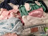 a pile of clothes that is sitting on a bed