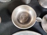 a lot of silver dishes and cups on the table