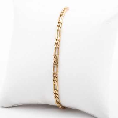 un bracelet en chaîne d'or posé sur un coussin blanc