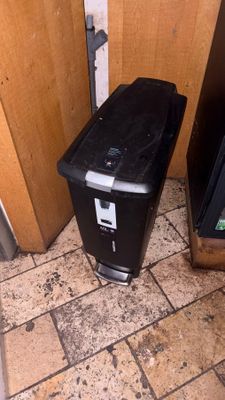 a black trash can sitting next to a television on the floor