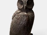 statue of an owl sitting on a tree stump on a white background