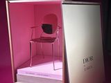 a box with a chair inside of it on a pink surface