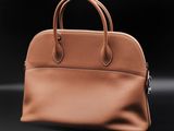 a brown leather handbag on a black background
