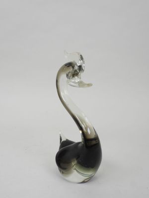 une figurine de cygne en verre noir et blanc posée sur une surface blanche
