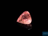un diamant rose sur une surface noire, avec un fond noir