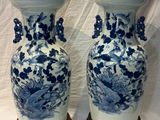 pair of blue and white vases on wooden stands on a white background