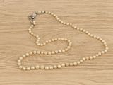 pearl necklace on a wooden table with a cross in the middle