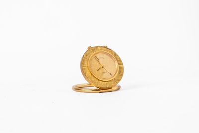 une image représentant une horloge en or posée sur un anneau en or