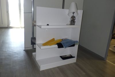 une étagère blanche sur laquelle sont posés des vêtements, dans une pièce