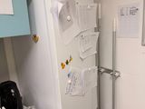 a refrigerator in the corner of a kitchen with a bunch of papers on the door